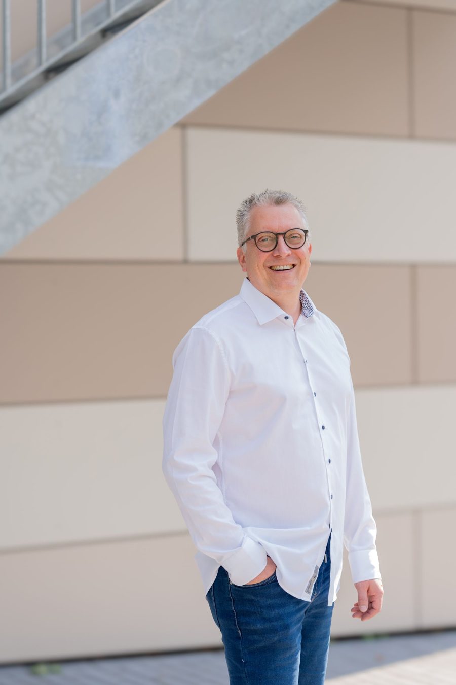 Jörg Hillemanns, Unternehmensberater aus Euskirchen, lächelnd in weißem Hemd vor einer hellen Fassade